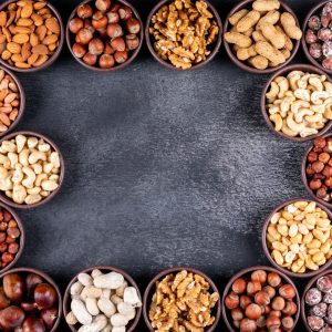 Some of assorted nuts and dried fruits with pecan, pistachios, almond, peanut, in a mini different bowls on black stone background, top view. copy space for text